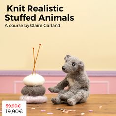 a teddy bear sitting on top of a pile of rocks next to a knitting needle