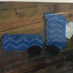 a pair of sunglasses and case sitting on top of a wooden table next to a bag