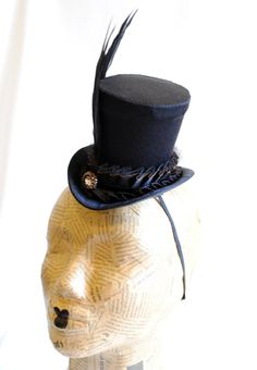 Elegant, dark, victorian...This beautiful gothic mini top hat is made with black satin and it is adorned with pleated ribbon and tulle trimming, three iridescent rooster feathers and a sparkling bronze button. Perfect for your victorian, gothic or steampunk costume. This mini top hat is fully lined with satin and attaches to the head with thin elastic that goes under the hair, to ensure stability and achieve that perfect angled look. Measurements : 3.5 inches (9 cm) tall , 5.5 inches (14 cm) fro Dark Victorian, Rooster Feathers, Mini Top Hat, Steampunk Costume, Mini Top, Victorian Gothic, Top Hat, Black Satin, Headpiece