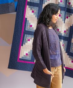 a woman standing in front of two quilts on the wall and looking at something