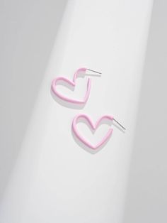 two pairs of pink heart shaped earrings on a white surface, with one ear pin in the shape of a heart