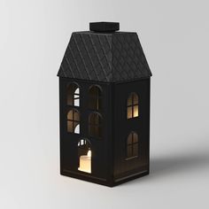 a small black house with windows and a light inside the window is lit up at night