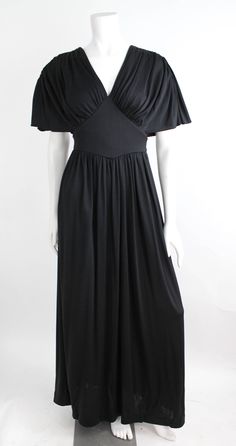 "Gorgeous draped goddess gown from the 1970's. Constructed of nylon jersey with a medium weight and soft hand. Features a v-shaped neckline with gathers at the bodice and sleeves, banded waist, and waistband that ties at the back. The bodice has a fitted underlayer with the sleeve draped over it. Sleeves are sloped at the shoulders. Center back zipper closure.  DETAILS Condition: More than excellent! Freshly laundered and ready to wear.  Label + Era: n/a; 1970s Fabrication: 100% Nylon Color: Bla Fitted Empire Waist Maxi Dress, Fitted Maxi Dress With Empire Waist, Fitted Solid Color Maxi Dress With Empire Waist, Vintage V-neck Evening Maxi Dress, Fitted Ruched Maxi Dress With Empire Waist, Vintage V-neck Maxi Dress For Evening, Fitted 1970s Dress With Empire Waist, 1970s Empire Waist Fitted Dress, 1970s Fitted Empire Waist Dress