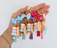 a hand holding several different colored bows and tassels on it's fingers