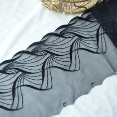 black and grey fabric with wavy design on white table cloth next to gold plated object