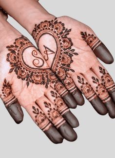 two hands with henna designs on them, one is showing the letter s and the other