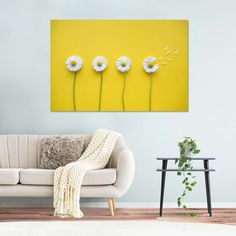 three daisies on a yellow wall in front of a couch