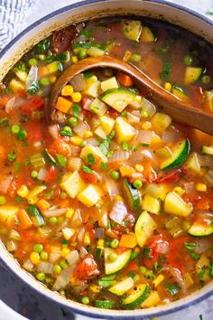 a pot filled with vegetable soup and a wooden spoon