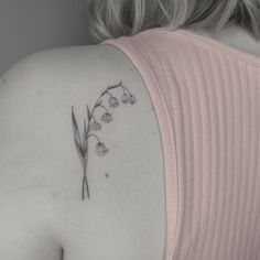 the back of a woman's shoulder with lily of the valley tattoo on it