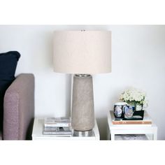 a lamp sitting on top of a white table next to a purple couch and end table