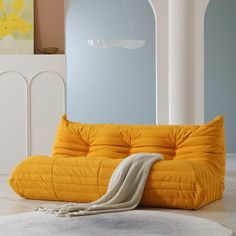 a yellow couch sitting on top of a white rug