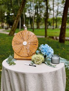 a wooden wheel on top of a table next to flowers and writing utensils