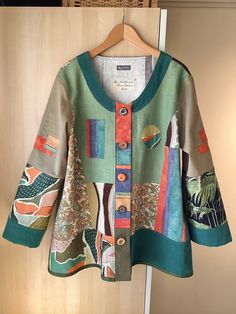 "This unique patchwork wearable art jacket in size M-L is handmade from carefully selected upcycled textiles from clothes and homedecor in cotton. The colours are mainly bluish green and khaki green with pops of terracotta red and peach. There is also applique embellishments. The colours complement each other in a lovely suttle way. The jacket is not lined, the seam allowances are sewn down with a wide threestep zigzag which makes at decorative topstitch around all the pieces. The jacket has a l Applique Clothes, Art Jacket, Quilted Clothing, Wearable Art Clothing, Upcycled Textiles, Concept Clothing, Art Clothing, Artist Outfit, Patchwork Jacket