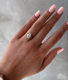 a woman's hand with pink manicured nails and a diamond ring on it