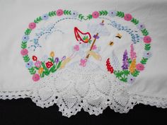 an embroidered tablecloth with flowers and a lady holding an umbrella on it's side