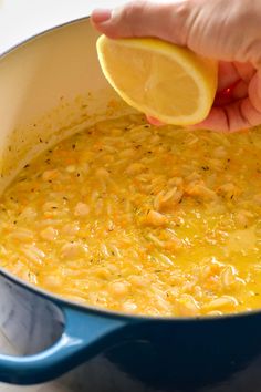 someone is squeezing a lemon into a pot of soup