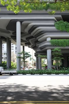 a car is driving down the street under an overpass with plants growing on it