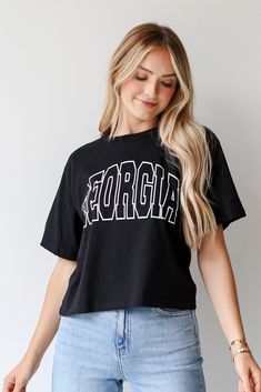 Calling all Dawgs fans, the Black Georgia Block Letter Cropped Tee was made just for you! This comfy tee is designed with a soft and stretchy knit. It features a crew neckline, short sleeves, a relaxed fit, and the word "Georgia" on the front. Style the Black Georgia Block Letter Cropped Tee with your favorite distressed denim and sneakers for the perfect game day look! Soft + Stretchy Knit Fabrication "Georgia" Graphic Crew Neckline Short Sleeves Relaxed Fit 100% Cotton Machine Wash Cold, Tumbl Trendy Game Day Short Sleeve T-shirt, Trendy Short Sleeve T-shirt For Game Day, College Stretch T-shirt With Letter Print, Casual T-shirt For Game Day In Spring, Black Crew Neck Cropped T-shirt, Black Cropped T-shirt With Crew Neck, Stretch Crew Neck T-shirt With Text Print, Collegiate Relaxed Fit Top With Text Print, Cropped Crew Neck T-shirt With Graphic Print For College