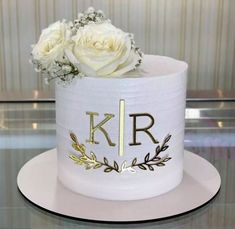 there is a white cake with gold letters and flowers on the top, sitting on a plate