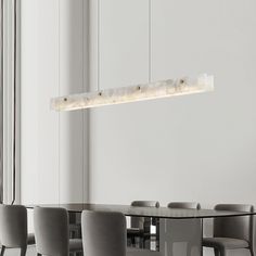 a dining room table with chairs and a long rectangular light fixture hanging from the ceiling