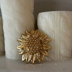 a golden flower brooch sitting on top of a table next to two white candles