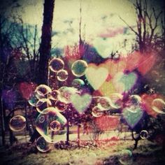 soap bubbles are floating in the air near trees and hearts on a sunny day with blue sky