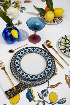 a table topped with plates and silverware next to lemons