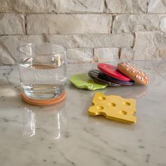 three different cheese coasters and a glass of water on a marble counter top with a brick wall in the background