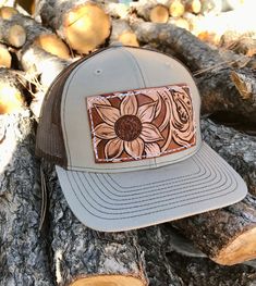 A tan and brown Richardson Trucker hat decked out with a sunflower and some vines on a leather patch! These Richardson  hats are super comfortable and have an adjustable snap back.  PLEASE READ: This item is for pre-ordering, and is made to order! Once purchased, this item will take approximately two weeks to re-create. Item will be a close replica, but each one will have slight variances in color, carving, etc. as I am not perfect, and leather is not perfect either! *All of HCL's leather produc Rustic Brown Hat For Outdoor, Western Style Brown Trucker Hat For Outdoor, Western Style Brown Trucker Hat With Flat Bill, Western Brown Trucker Hat With Flat Bill, Western Style Brown Snapback Hat, Western Brown Snapback Hat, Brown Western Trucker Hat With Flat Brim, Country Style Brown Trucker Hat With Curved Brim, Country Style Brown Trucker Hat