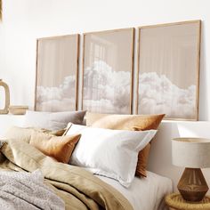 a bed with two pictures hanging above it and pillows on the headboard next to each other