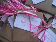 pink streamers tied to brown envelopes with wedding cards on them and paper tags