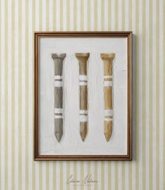 three framed objects are hanging on the wall in front of a beige striped wallpaper