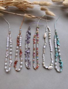 five necklaces are lined up next to each other on a table with dried wheat