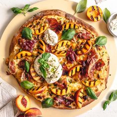 a pizza topped with lots of toppings sitting on top of a plate next to sliced peaches