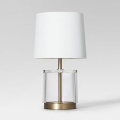 a table lamp with a white shade on the base and a gold metal frame around it