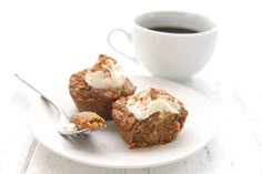 two muffins on a white plate with a cup of coffee