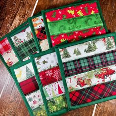 four quilted placemats with christmas designs on them sitting on a wooden table