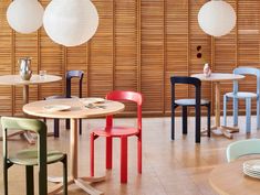 several different colored chairs and tables in a room with bamboo blinds on the wall behind them