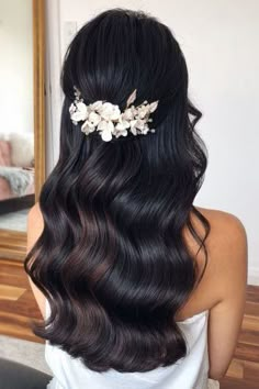 the back of a woman's head with long hair and flowers in her hair