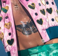 a close up of a person with tattoos on their stomach and wearing a pink jacket