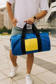 a man carrying a blue and yellow duffel bag