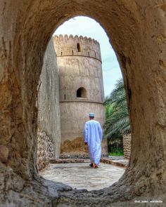 a man standing in front of a stone tower