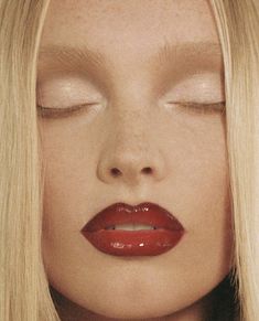 a woman with long blonde hair and red lipstick is looking down at the camera while she has her eyes closed