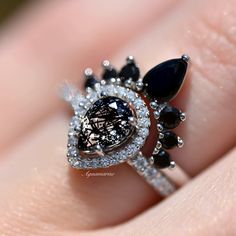 a woman's hand with a diamond and black stone ring on top of her finger