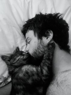 a man laying in bed next to a cat