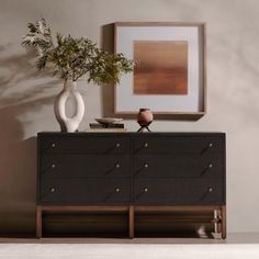 a white vase sitting on top of a black dresser