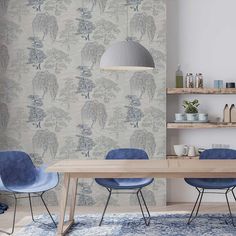 a dining room with blue chairs and a wooden table in front of a wallpapered wall