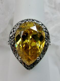 Simulated Yellow Citrine Gemstone Teardrop RingTear Vic Design#D28 Inspired by Victorian and Art Deco designs, this high-quality filigree ring is handcrafted in sterling silver. This teardrop ring is set with an 8 carat pear cut flawless yellow citrine simulated gemstone. The gem is 16mm (~5/8") x 12mm (~1/2"). The gorgeous stone has a lovely vibrant color. The inside of the band is marked 925 for sterling silver. Notice the beautiful filigree of the silver setting. This is a ring with beauty an Yellow Teardrop Wedding Ring, Pear-shaped Yellow Ring For Gift, Yellow Pear-shaped Gemstone Jewelry, Yellow Teardrop Ring For Formal Occasions, Ornate Yellow Jewelry For Wedding, Ornate Yellow Jewelry For Formal Occasions, Ornate Yellow Wedding Jewelry, Yellow Teardrop Rings For Anniversary, Yellow Teardrop Jewelry For Formal Occasions