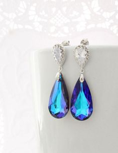 "If you are looking for purple earrings to make a statement, these Luxury Heliotrope color Swarovski Earrings are your best option! They are also a big favorite for Peacock themed Weddings and the teardrop crystals feature multiple colors, predominantly Purple and Turquoise. A must have for your Purple outfit! These luxury Teardrop Earrings are made of sparkly Purple Genuine Swarovski crystals that hang from nickel free Solid Sterling Silver post earrings (the whole earring, not just the post!) Elegant Peacock Earrings For Wedding, Elegant Peacock Colored Earrings For Wedding, Elegant Peacock Colored Earrings For Gift, Elegant Peacock-colored Earrings As A Gift, Elegant Peacock-colored Earrings For Gift, Peacock Colored Earrings For Wedding, Peacock Wedding Theme, Earrings To Make, Turquoise Earring