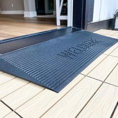 a door mat on the ground in front of a house with wood floors and doors